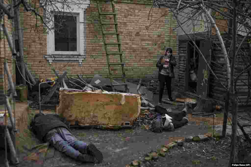Ira Gavriluk holds her cat on April 4 as she stands over the bodies of her husband, brother, and another man who were killed outside her home in Bucha, on the outskirts of Kyiv.