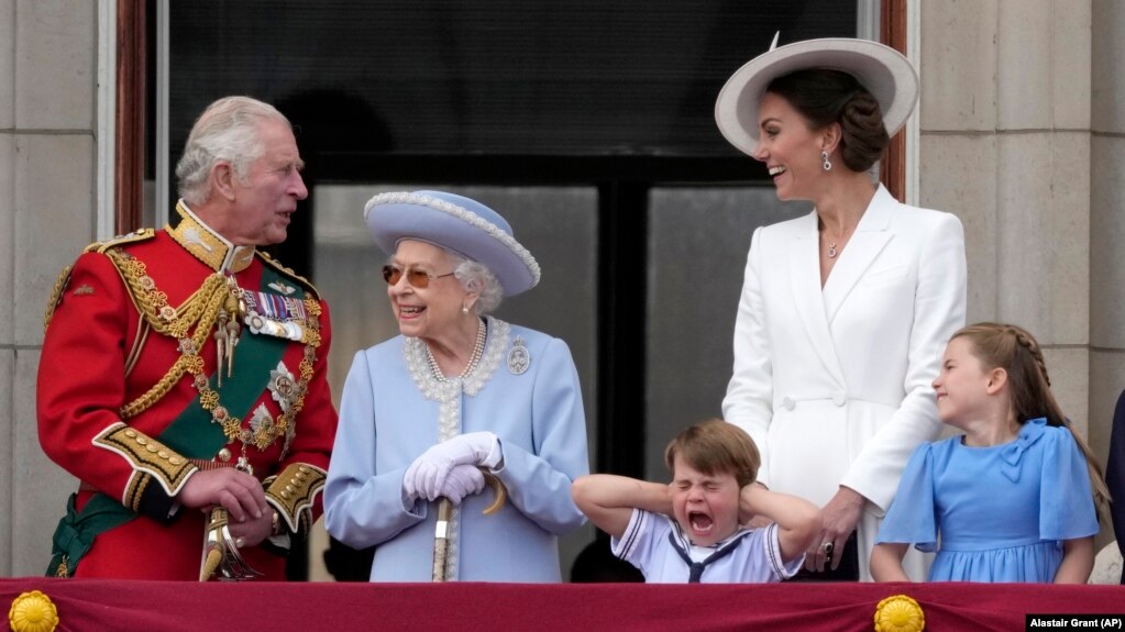  Британският принц Чарлз (вляво), кралица Елизабет, принц Луи, майка му Кейт, херцогинята на Кеймбридж, и нейната щерка принцеса Шарлот стоят на балкона на Бъкингамския замък в първия от четирите дни на тържествата по отбелязване на платинения празник на кралицата, 2 юни 2022 година 