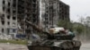 Российский военный на танке с награбленными вещами в Попасной, Луганская область. На заднем плане – разрушенные жилые дома. 26 мая 2022 года