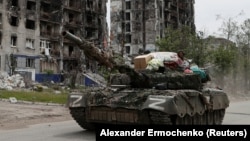 Pro-Russian troops drive a tank past a destroyed residential building in the town of Popasna in Ukraine's Luhansk region on May 26.