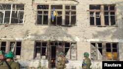 Soldații ucraineni stau în fața unei clădiri, cu un steag ucrainean, din satul Blahodatne, pe care Kievul a pretins că l-a eliberat pe 11 iunie.