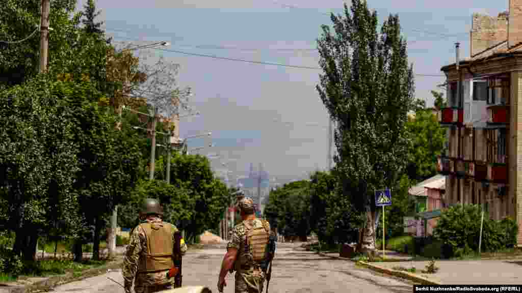 Українські військові йдуть по одній з вулиць Лисичанська, на горизонті місто Сєвєродонецьк, за який зараз точаться запеклі бої