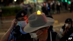 Policija oko muškarca koji nosi šešir sa LED svijećom u hongkonškom Victoria Parku, subota, 4. juna 2022.