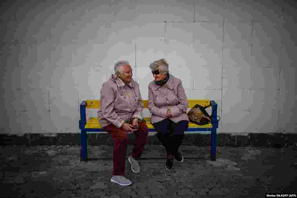 Idős emberek beszélgetnek egy padon üldögélve Szlavuticsban május 28-án