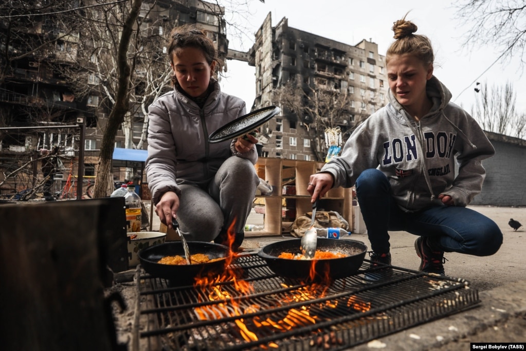 Gratë gatuajnë ushqim jashtë mbi një zjarr në Mariupol më 3 prill. Gazi, energjia elektrike dhe uji u ndërprenë ndërsa forcat ruse u futën në qytet.