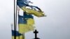 Damaged Ukrainian national flags flutter in the wind at a cemetery in Chernihiv in April.