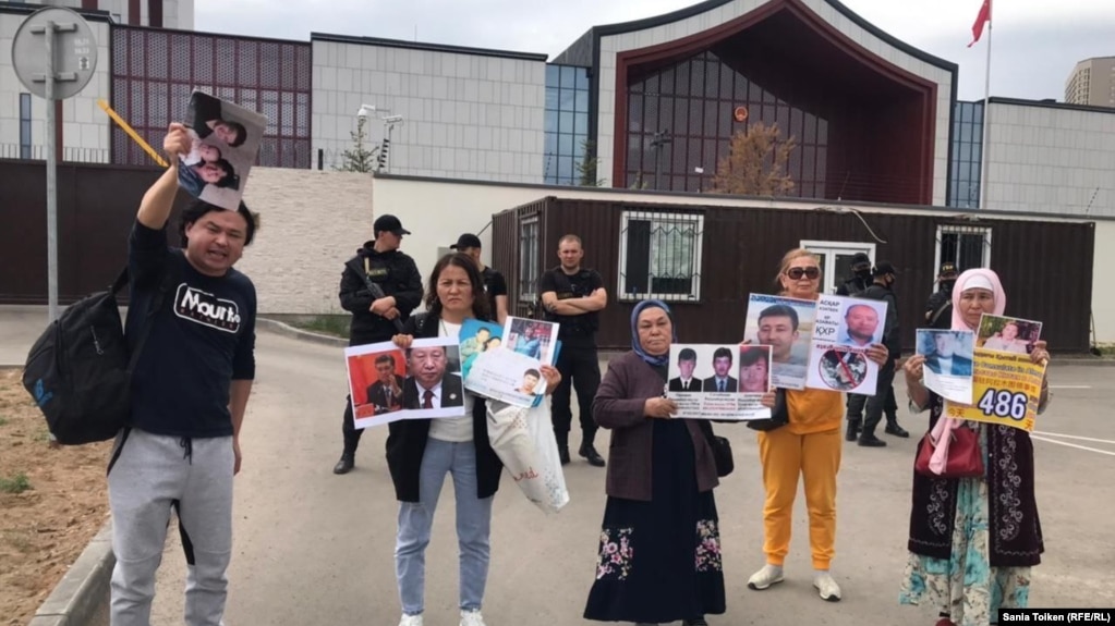 Казахи, требующие освободить задержанных в Китае родственников, держат плакаты с их фотографиями у посольства Китая в Казахстане. Нур-Султан, 8 июня 2022 года