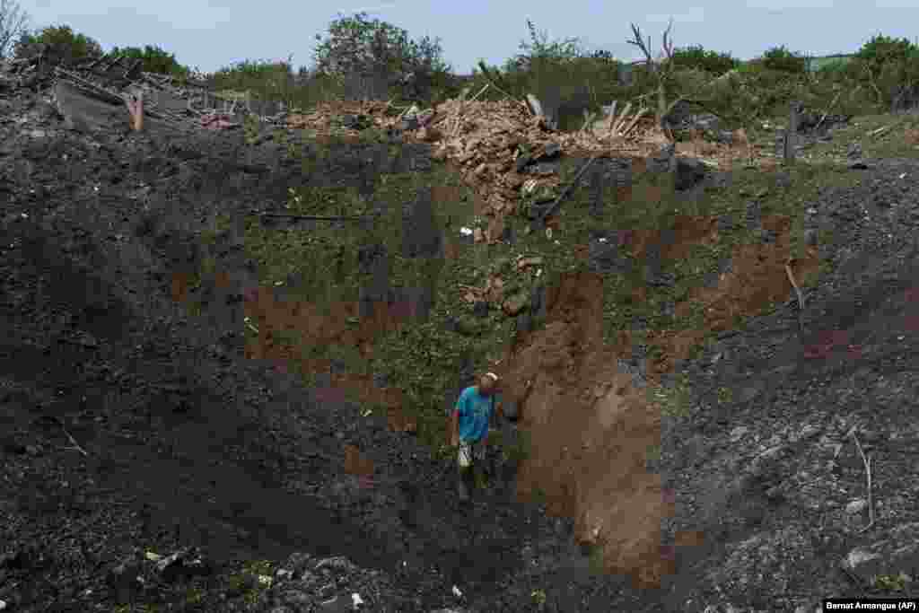 A man walks through a large crater caused by a Russian missile strike in Druzhkivka.&nbsp;
