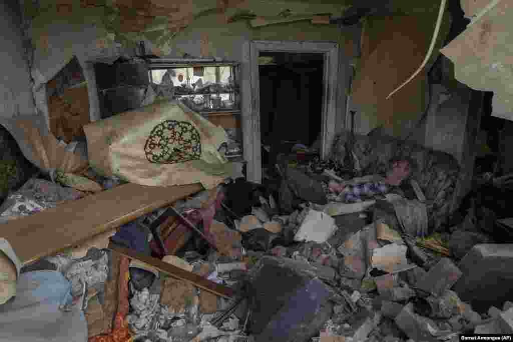 A Druzhkivka resident sits on a sofa inside a house damaged by a missile strike.