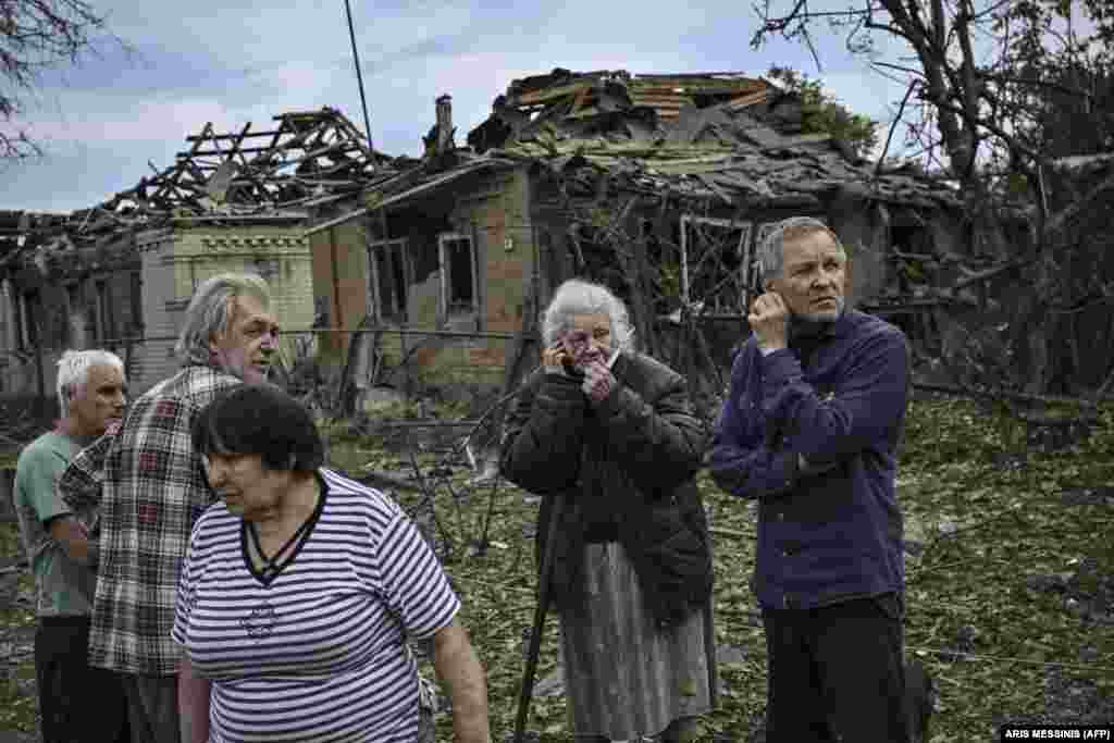 Stanovnici stoje ispred uništenih kuća, nakon što je starija žena ubijena u raketnom udaru.