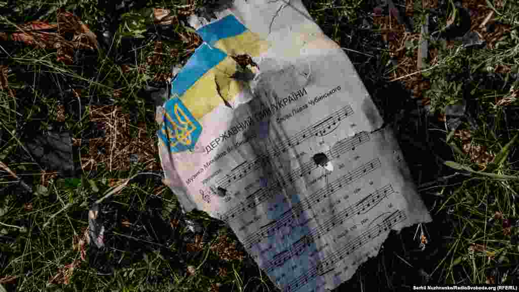 A damaged page of sheet music with the Ukrainian national anthem lies on the school grounds.