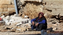 A woman rests near rubble in the Syrian town of Darat Izza in Aleppo Province on February 28.