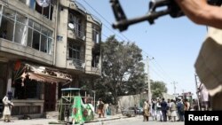 Taliban fighters stand guard at the site of a deadly attack on a Sikh temple in Kabul on June 18.