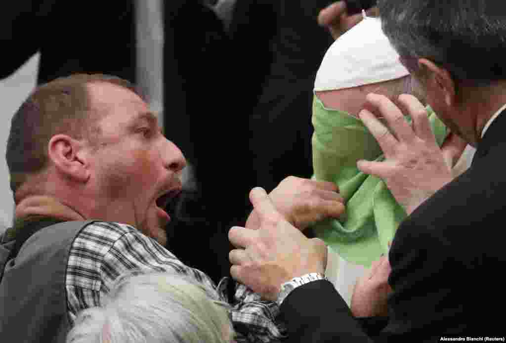 A man helps Pope Francis put on a neckerchief he gifted to the pope during a general audience at the Paul VI Hall at the Vatican. (Reuters/Alessandro Bianchi)