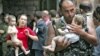 A soldier carries a baby and a woman follows him with another small child after the release of 26 women and their children in Beslan on September 2, 2004.