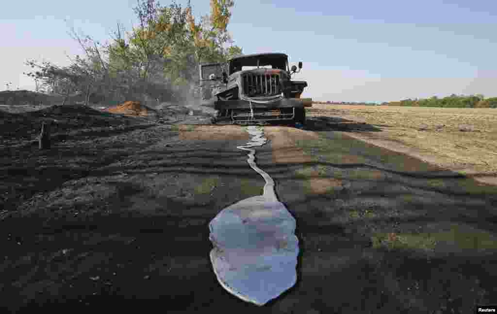 A puddle of melted material is pictured in front of a burned-out truck belonging to Ukrainian forces on a road near the village of Berezove, southwest of Donetsk. (Reuters/Maxim Shemetov)