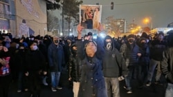 A protester holds up a photo of Iran's last shah, Mohammad Reza Pahlavi, and his wife, Farah Pahlavi, at a demonstration in Ektaban Town in western Tehran on January 9. 