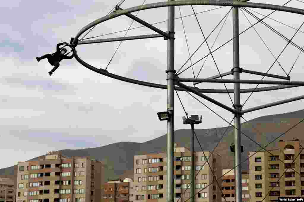 An Iranian boy wearing a protective face mask to help prevent the spread of the coronavirus rides a zip line at an amusement park in Tehran. (AP/Vahid Salemi)