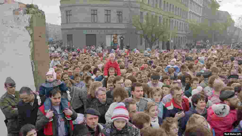 Людзі ідуць праз пралом у сьцяне 11 лістапада пасьля таго, як усходненямецкім салдатам загадалі адступіць, фактычна скончыўшы фізычнае разьдзяленьне паміж Усходнім і Заходнім Бэрлінам.