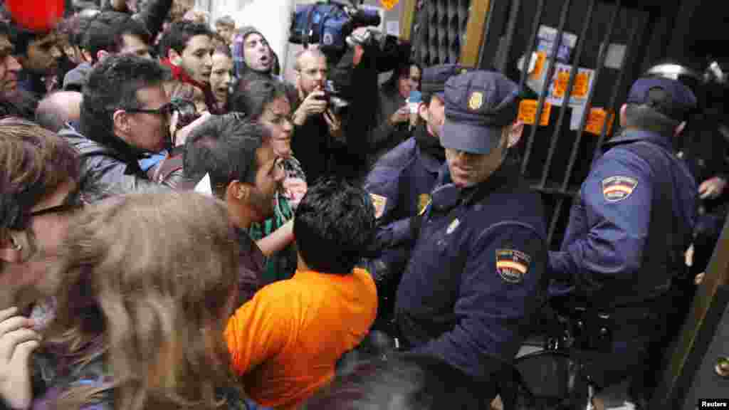 Protestors scuffle with police outside a branch of the Bank of Spain branch in Valencia.