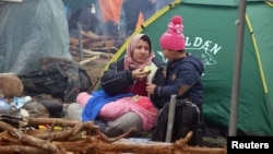 Мигрантка с детьми сидит у палатки в Гродненской области, неподалеку от границы с Польшей, Беларусь, 10 ноября 2021 года.