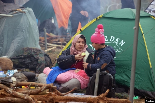 Migrantkinja i njena djeca odmaraju se pored šatora u bjeloruskoj Grodnenskoj oblasti, blizu granice s Poljskom, 10. novembar 2021.