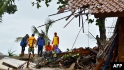 Officials look through the wreckage of damaged buildings in Carita, Indonesia, on December 23.