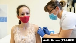 A Hungarian medic administers the Russian Sputnik V vaccine to a young woman at a hospital in Nyiregyhaza.