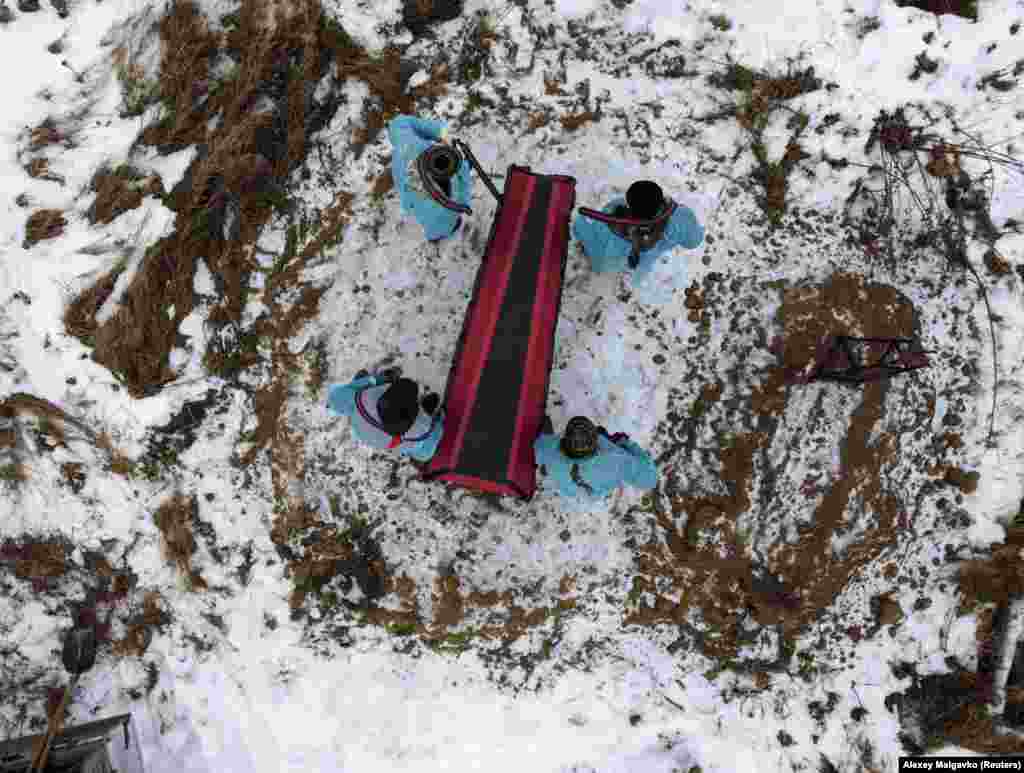 Amid a surge in COVID-19 deaths and infections, grave diggers wearing protective face masks bury a person who has no next of kin at a cemetery in the town of Tara in Russia&#39;s Omsk region.&nbsp;