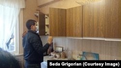 A plainclothes policeman searches through Seda Grigorian’s kitchen on November 6.