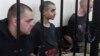 Aiden Aslin (left), Saaudun Brahim (center), and Shaun Pinner sit behind bars in a courtroom in Donetsk on June 9.