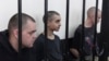 British citizens Aiden Aslin (left) and Shaun Pinner (right), along with Moroccan Saaudun Brahim (center), sit behind bars in a courtroom in Donetsk, eastern Ukraine, on June 9.