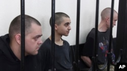 Két brit állampolgár, Aiden Aslin (balra) és Shaun Pinner (jobbra), valamint a marokkói Szádun Brahim (középen) egy donyecki bíróságon, Kelet-Ukrajnában 2022. június 9-én