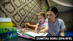 Ukrán édesanya olvas a kislányának egy moldovai menekülttáborban Chişinău mellett 2022. június 9-én