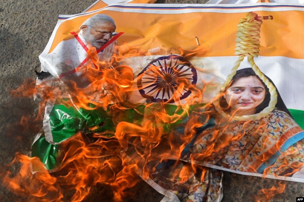 Protestuesit djegin një poster me fotografinë e kryeministrit indian, Narendra Modi, dhe ish-zëdhënëses së Partisë Bharatiya Janata, Nupur Sharma, gjatë një demonstrate ndaj diskursit të saj mbi Profetin Muhamed, në Karaçi më 9 qershor 2022.