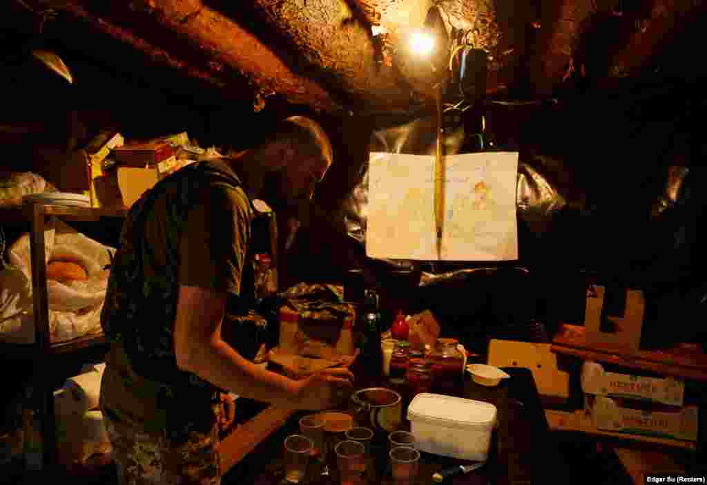 A Ukrainian soldier prepares coffee in a trench&#39;s dimly lit underground mess area on the front line near Mykolayiv.