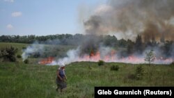 Žena posmatra kako trava gori nakon ruskog granatiranja u blizini grada Bakhmut u Donjeckoj oblasti 12. juna.