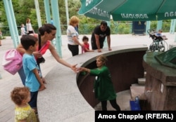 A worker hands fresh Borjomi mineral water to a tourist in the town's park. The spring water bubbles to the surface warm and slightly fizzy.