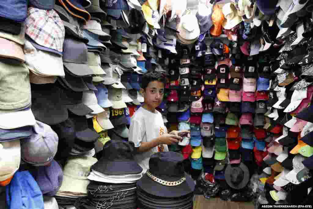 Një djalë iranian duke pritur klientët në një pazar kapelash në Teheran, më 13 qershor.