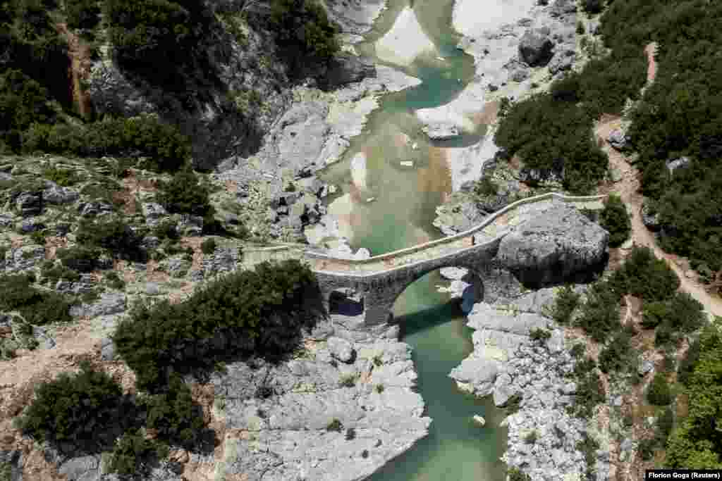 A person walks on the bridge at the Shushica tributary of the Vjosa River, in Brataj, Albania, on June 12.