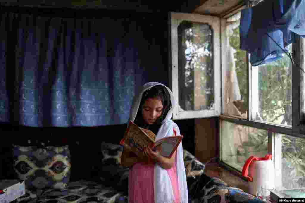 An Afghan girl reads a book inside her home in Kabul on June 13.