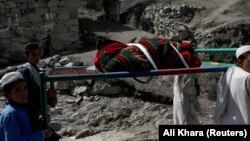 Afghan boys carry the body of a child victim of the earthquake in Golam Kot on June 23.