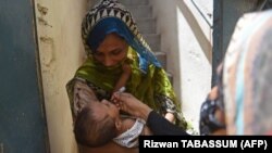 ПАКИСТАН- Здравствен работник аплицира капки вакцина против детска парализа на дете за време на кампањата за вакцинација против детска парализа од врата до врата во Карачи на 28 јуни 2022 година
