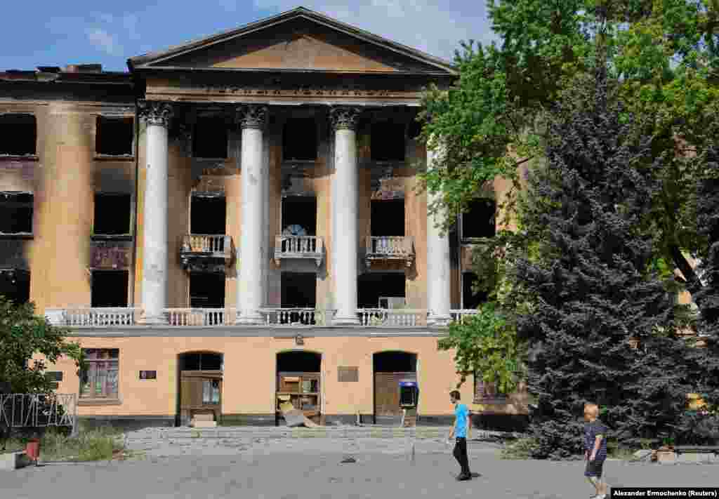 Stanovnici prolaze pored ruševina Lisičanskog državnog rudarsko-industrijskog koledža. Rusija je podvrgla grad na istoku Ukrajine dugotrajnom artiljerijskom bombardovanju dok je gušila linije snabdevanja svojih branilaca, primoravajući ih da se povuku. &nbsp;