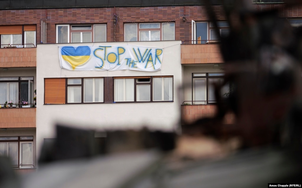 Një parullë kundër luftës e varur në një bllok apartamentesh me pamje kah automjetet ruse në Pragë. Ilya Kuchynskiy, një vullnetar ukrainas dhe anëtar i forcave të mbrojtjes territoriale të vendit, i cili po përgatiste ekspozitën për hapjen e saj më 11 korrik, i tha Radios Evropa e Lirë se ekspozita kishte për qëllim "t'u kujtonte njerëzve se lufta nuk është aq larg sa mendojnë ata. Ne nuk do të qëndrojmë, Republika Çeke është një nga të tjerat. Dhe të jeni të sigurt, [Rusia] nuk do të ndalet".