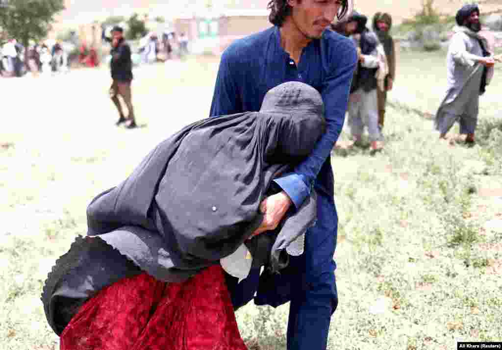 An Afghan woman is assisted to an evacuation helicopter after losing some of her relatives in the earthquake in the Gayan district.