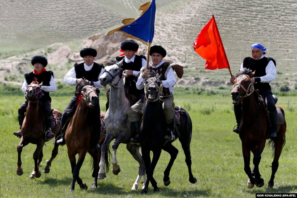 Кыргызские всадники с флагами мчатся в предгорной долине