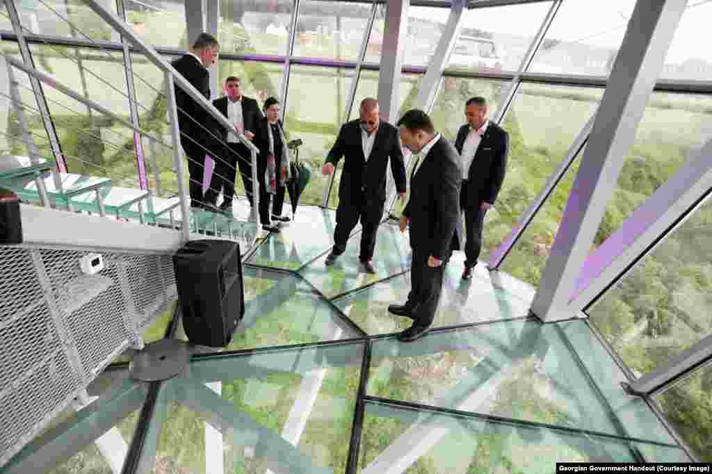 Prime minister Gharibashvili (second from right) looks through the glass floor of the main structure in the center of the bridge.&nbsp;