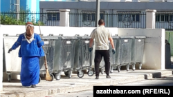 Aşgabadyň etrapçalarynyň birinde zibil çeleklerini arassalaýan arassaçylyk işgärleri (Arhiwden alnan illýustrasiýa suraty)