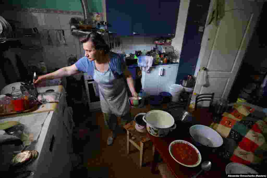 Olga Risanova, în vârstă de 60 de ani, pregătește mâncare în bucătăria sa de la subsolul unei clădiri din Severodonețk, 30 iunie 2022.